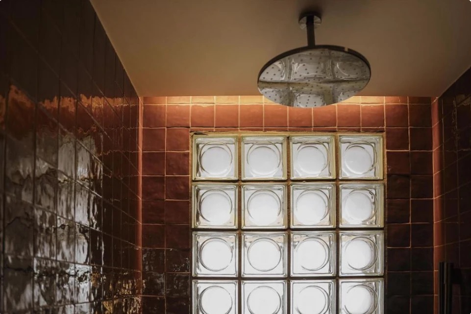 Detalle de azulejo rojizo en ducha de Thompson Sevilla